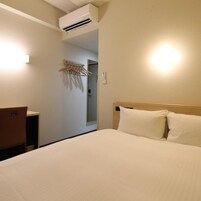 Una habitación de hotel con cama, escritorio y aire acondicionado.