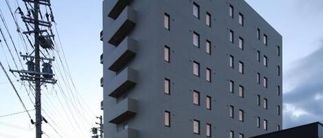 A multi-story hotel with a prominent 'AB HOTEL' sign, a covered entrance, and a parking area.