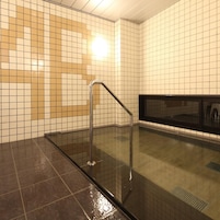 A tiled bathroom with a glass shower enclosure and a metal handrail.