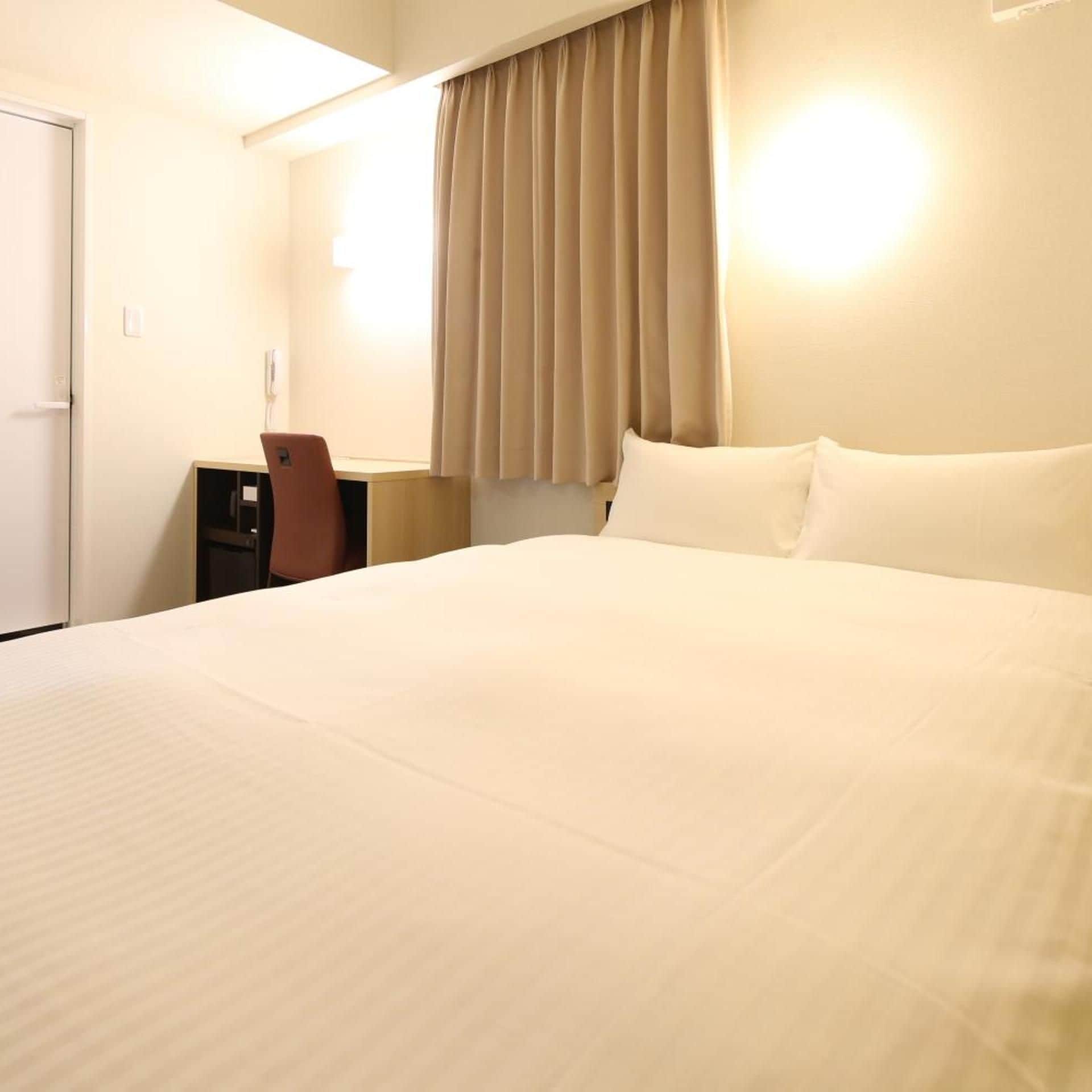 A hotel room with a large bed, a desk, and a chair.
