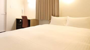 A hotel room with a large bed, a desk, and a chair.