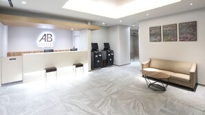 Un espace d’accueil d’hôtel au design moderne, comprenant un comptoir d’accueil, un canapé et des œuvres d’art accrochées au mur.