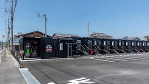 Una fila de contenedores negros de hotel con un cartel que dice 'The Yard' y 'R9 Hotels Group' en la planta baja.