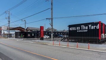 Un hotel con un cartel grande y negro que dice 'HOTEL R9 The Yard R9 HOTELS GROUP' y un estacionamiento cercado.