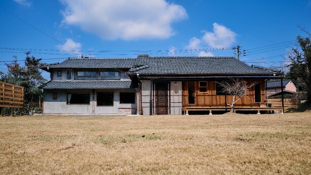 A traditional two-story house with a tiled roof and a wooden porch.