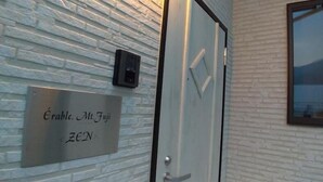 Una porta amb una placa que diu 'Érable. M. Fuji ZEN' i un petit dispositiu fixat a la paret.