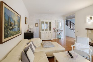 Un salon avec un canapé, une table, un meuble et un tableau accroché au mur.