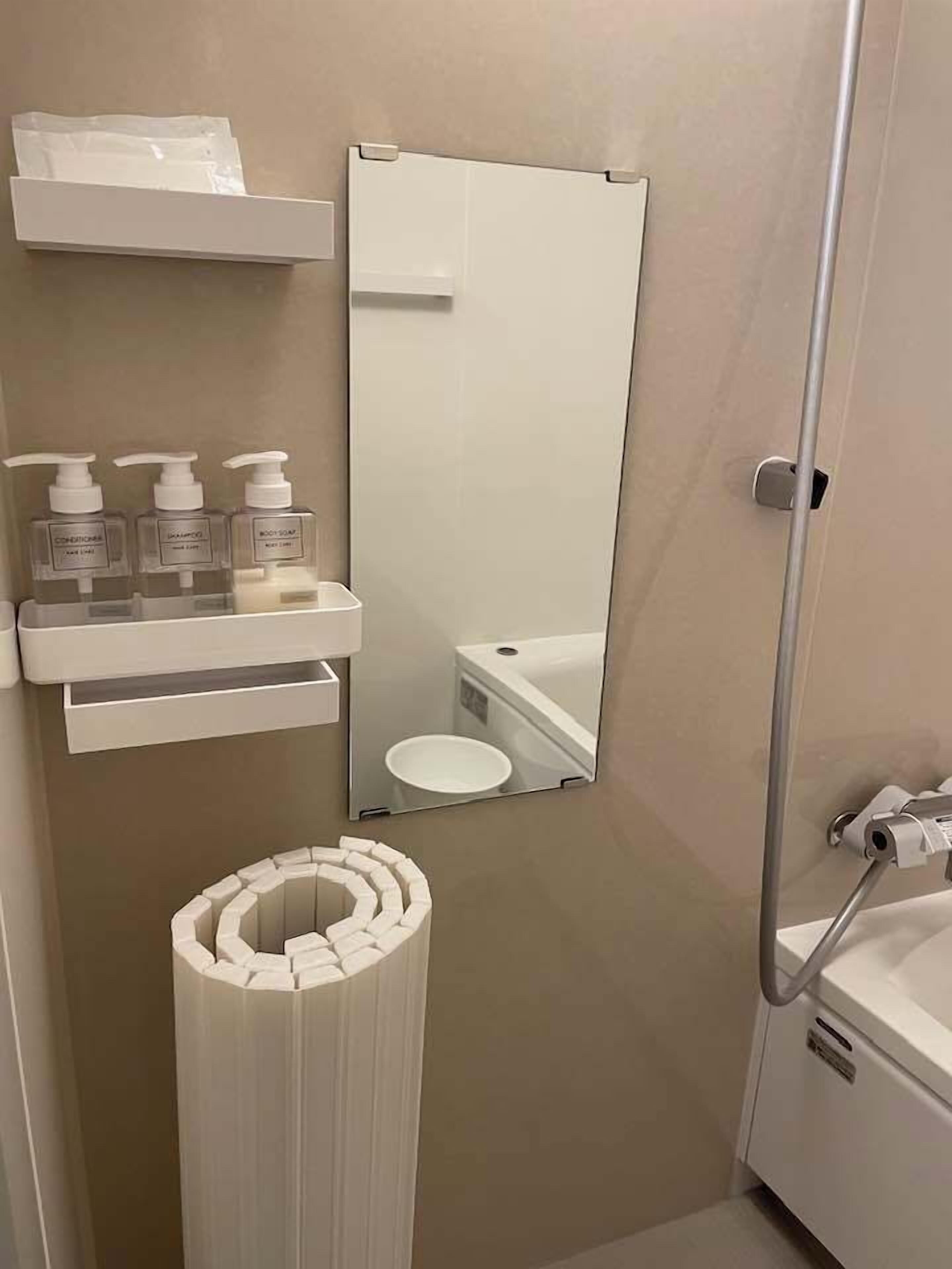 Een badkamer met toilet, wastafel, spiegel en wc-papierhouder.