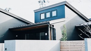 Una casa moderna con techo inclinado, cerca de madera y un pequeño jardín.