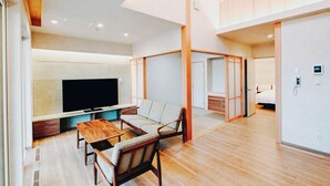 Una sala moderna con suelo de madera, un televisor de pantalla plana, una mesa de comedor de madera y un sofá.