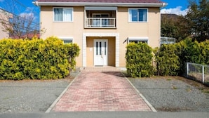 A two-story residential building with a red brick pathway leading to the entrance, surrounded by greenery. - Ma Maison Mt. Fuji Kawaguchiko (Fujikawaguchiko)