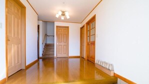 A hallway with wooden flooring, a staircase, and a door at the end. - Ma Maison Mt. Fuji Kawaguchiko (Fujikawaguchiko)