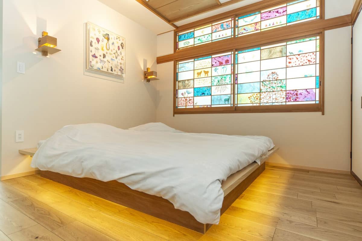 Un dormitorio con cama, un vitral y una lámpara de pared.