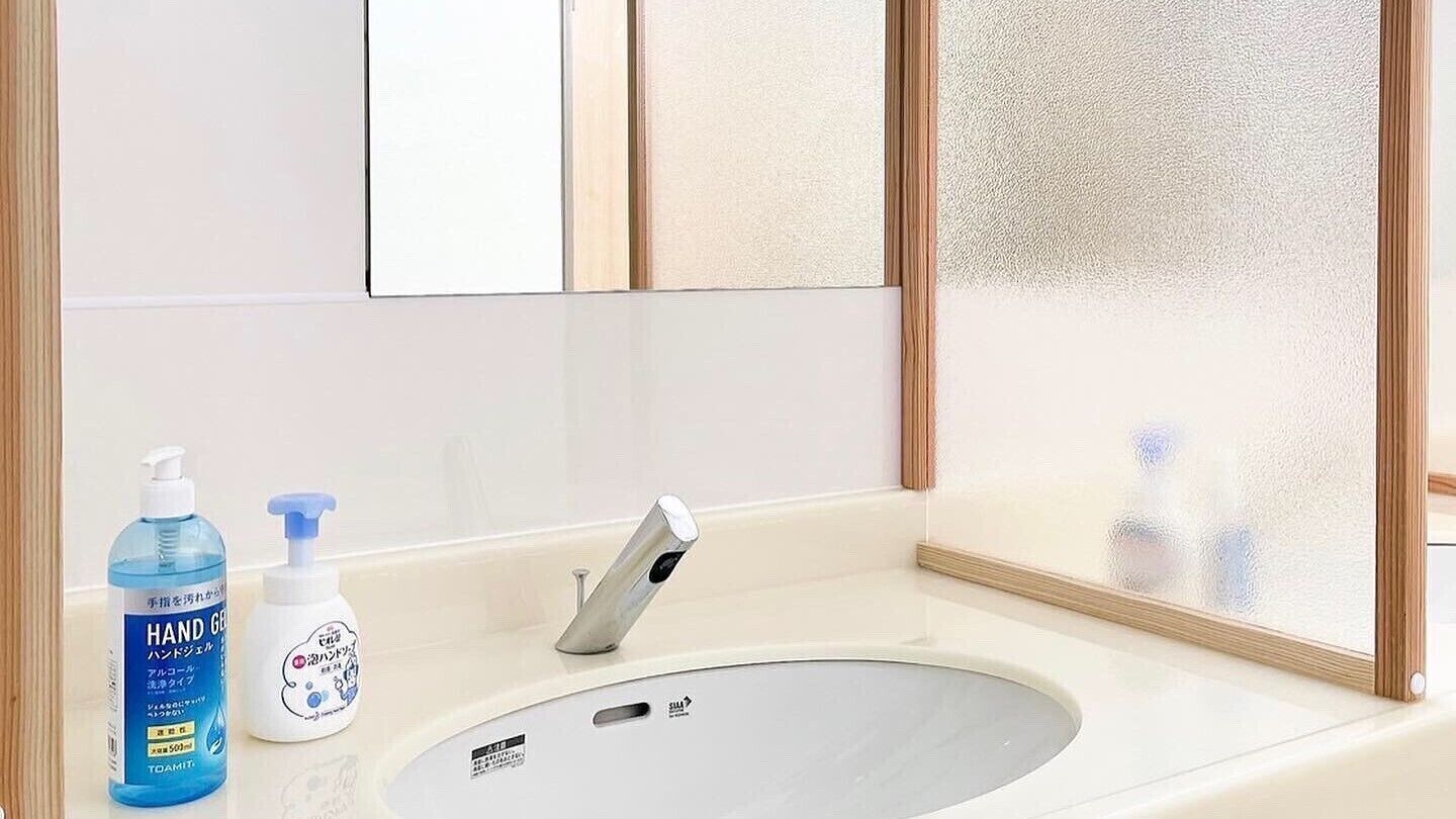 Une salle de bain équipée d’un lavabo, d’un miroir et de deux flacons de gel hydroalcoolique.