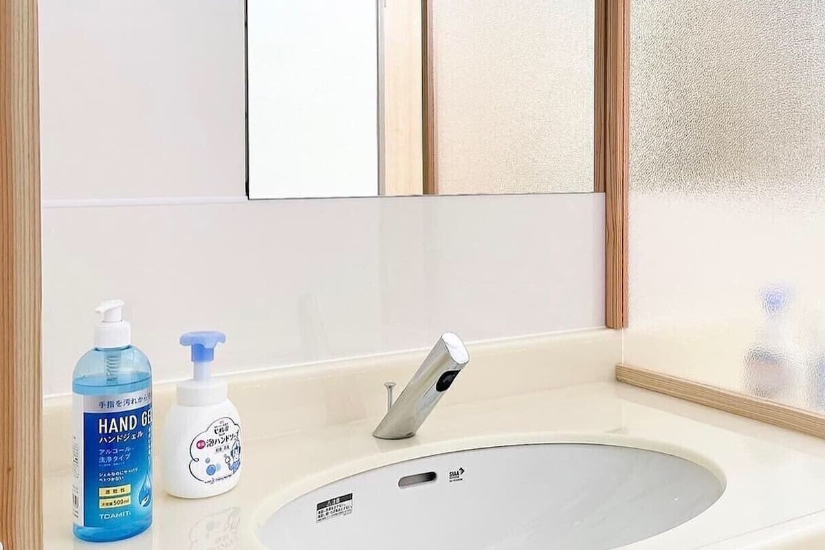 Une salle de bain équipée d’un lavabo, d’un miroir et de deux flacons de gel hydroalcoolique.