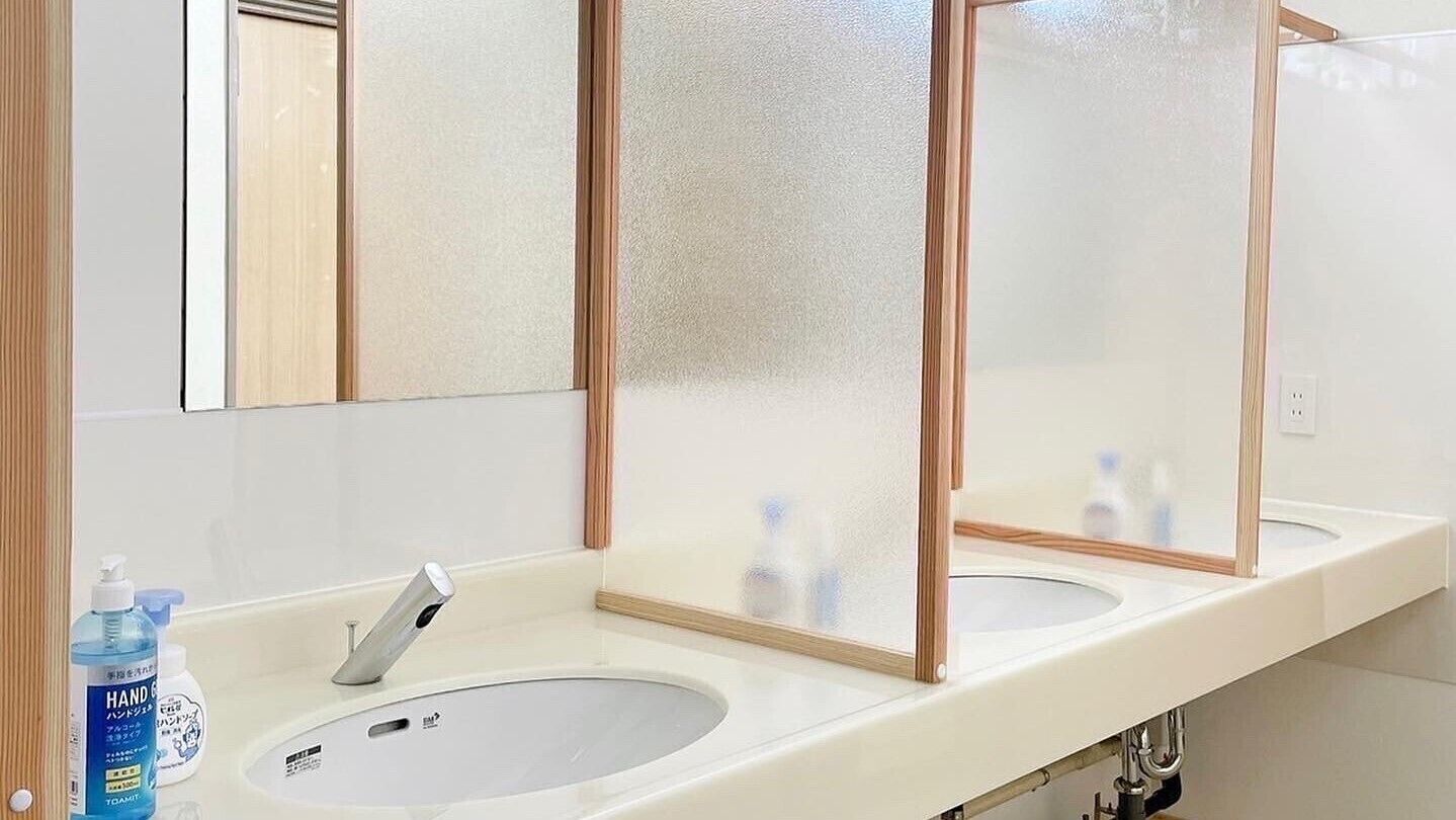 Une salle de bain avec deux lavabos, un miroir et un distributeur de savon liquide.