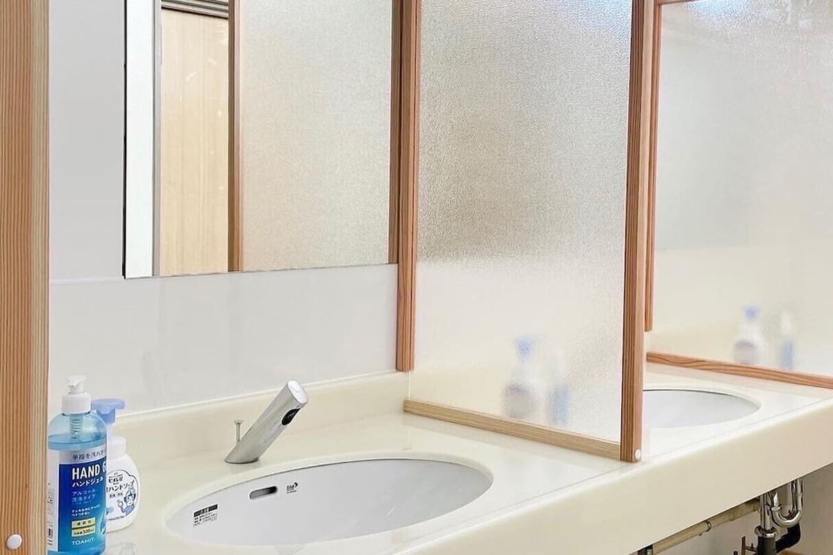 Une salle de bain avec deux lavabos, un miroir et un distributeur de savon liquide.