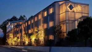 A modern building with a prominent logo, vertical windows, and a well-lit facade. - Hotel Yukari-no-mori Kawaguchiko (Fujikawaguchiko)