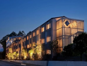 Un edificio moderno con un logotipo destacado, ventanas verticales y una fachada bien iluminada.