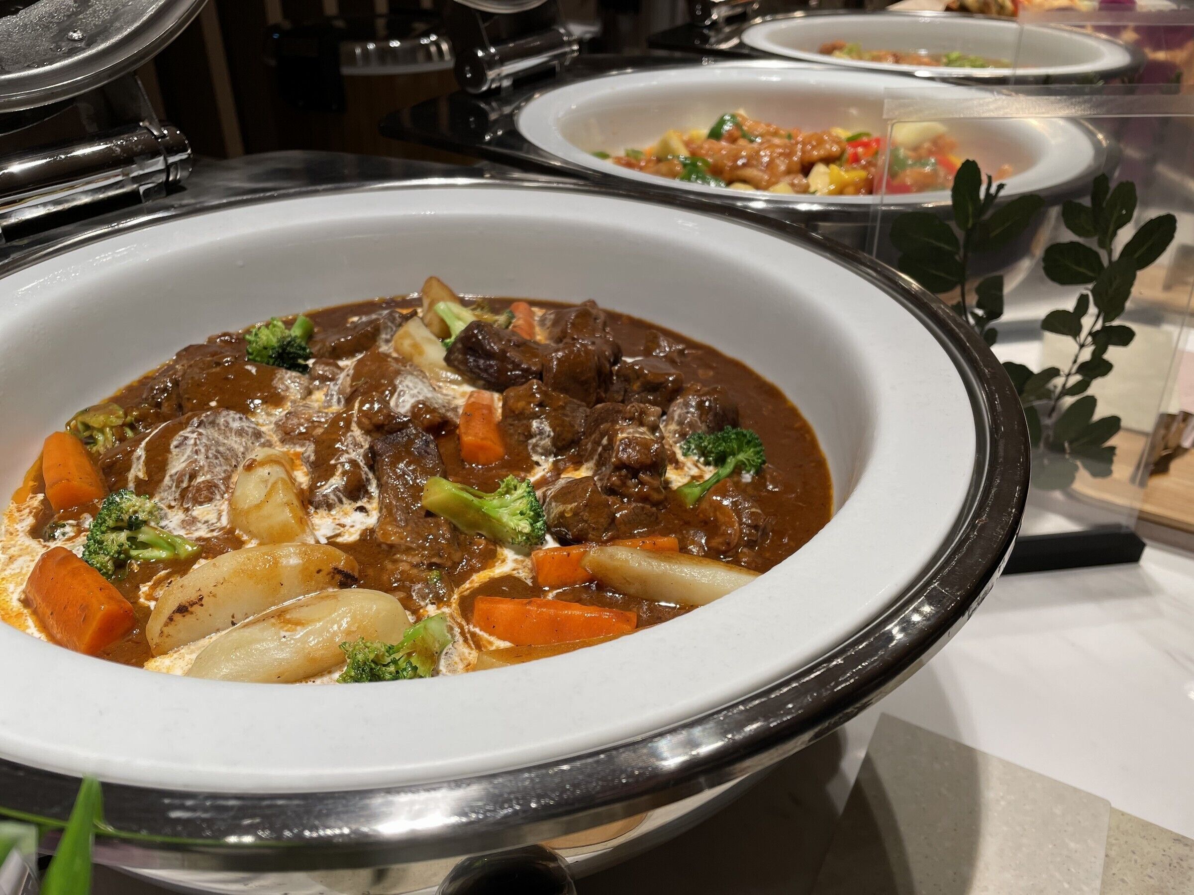 A buffet with a variety of dishes, including a beef stew with vegetables.