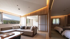 A modern hotel room with a sofa, a bed, a wooden floor, and a view of a mountain. - Hotel Yukari-no-mori Kawaguchiko (Fujikawaguchiko)