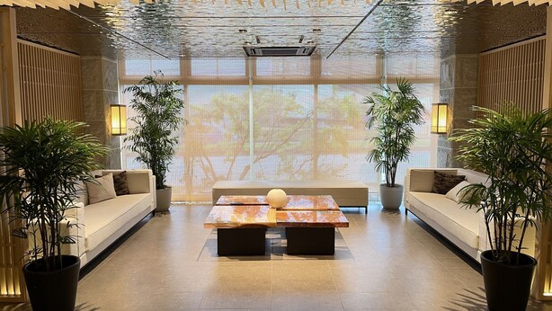 A modern lobby with a central seating area, two potted plants, and a large projection screen. - Hotel Yukari-no-mori Kawaguchiko (Fujikawaguchiko)