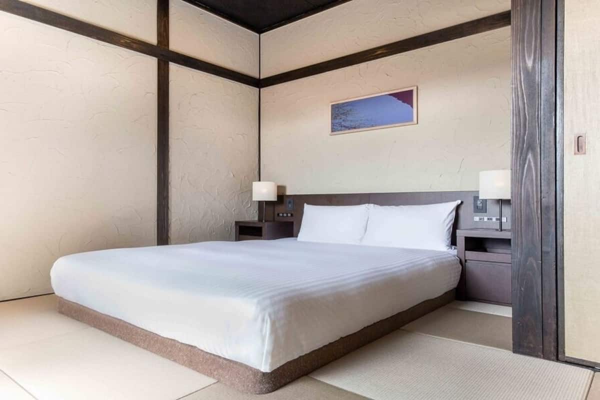 A hotel room with a bed, nightstands, a lamp, and a painting on the wall.