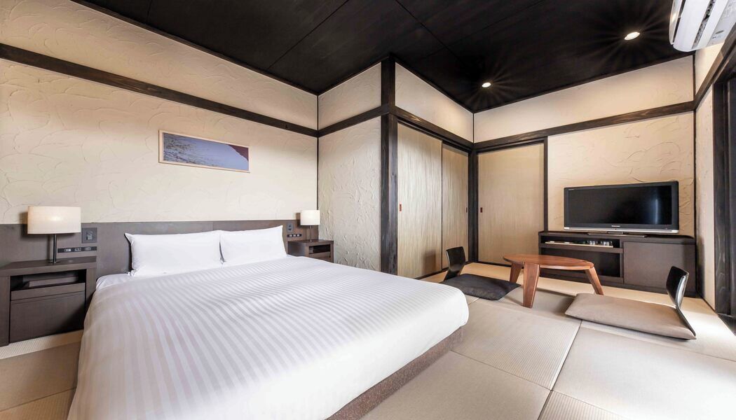 Une chambre d’hôtel avec un grand lit, une télévision, un bureau et une chaise.