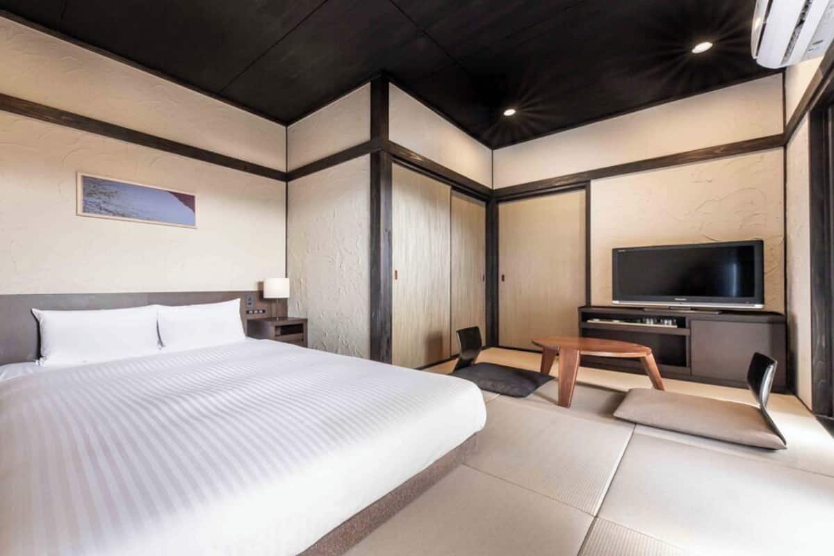 A hotel room with a large bed, a TV, a desk, and a chair.