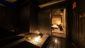A wooden interior with a bed, a nightstand, and a small table. - Nagomi Tsuki (Beppu)