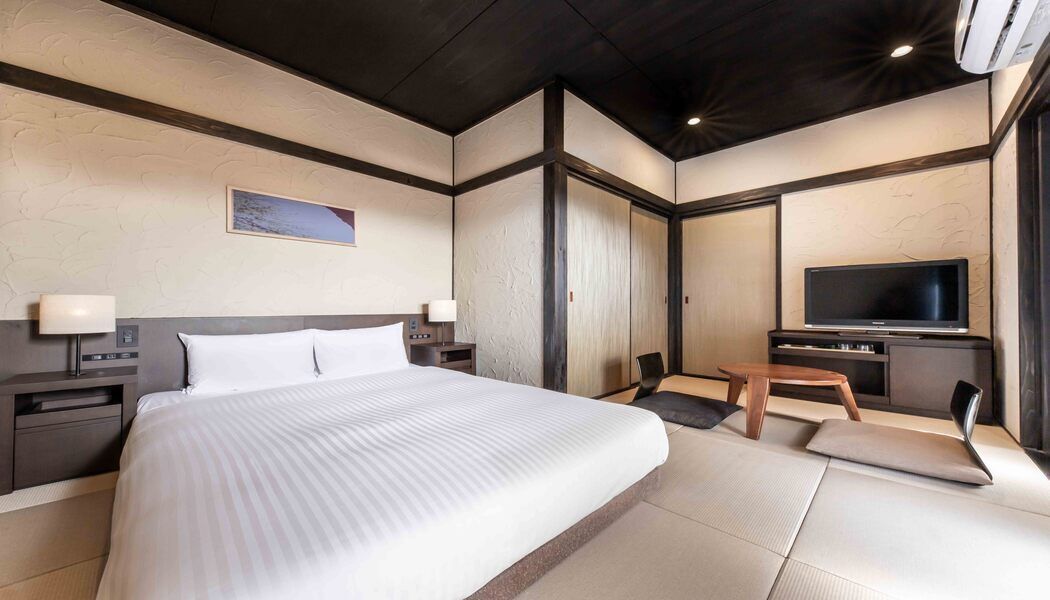 Une chambre d’hôtel avec un grand lit, une télévision, un bureau et une chaise.