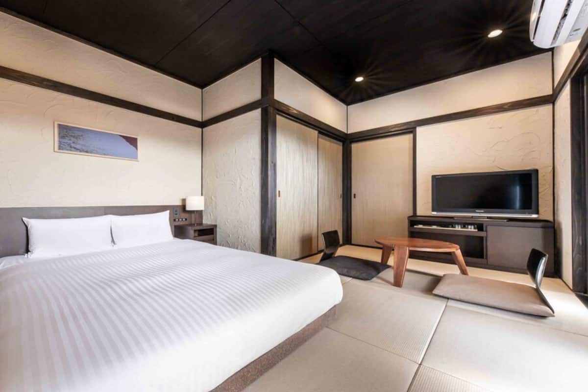A hotel room with a large bed, a TV, a desk, and a chair.