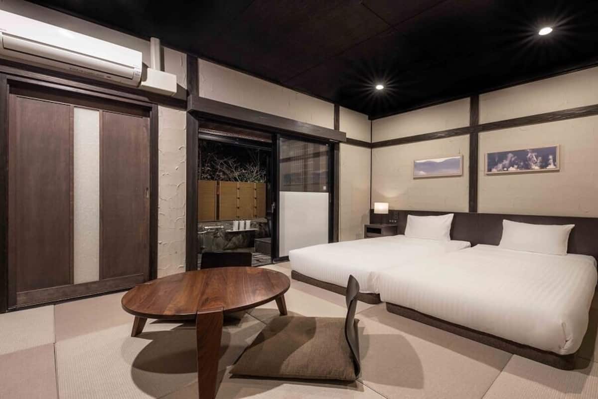A hotel room with a bed, bedside tables, a round table, and a sliding door.
