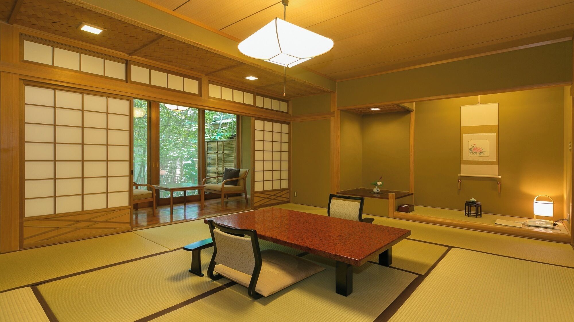 Una habitación japonesa tradicional con suelo de tatami, una mesa baja, sillas, una puerta corredera y un colgador con luz.