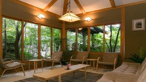 A room with large windows, wicker furniture, a wooden ceiling, and a hanging light fixture. - Yufuin Onsen Hinoharu Ryokan (Yufu)