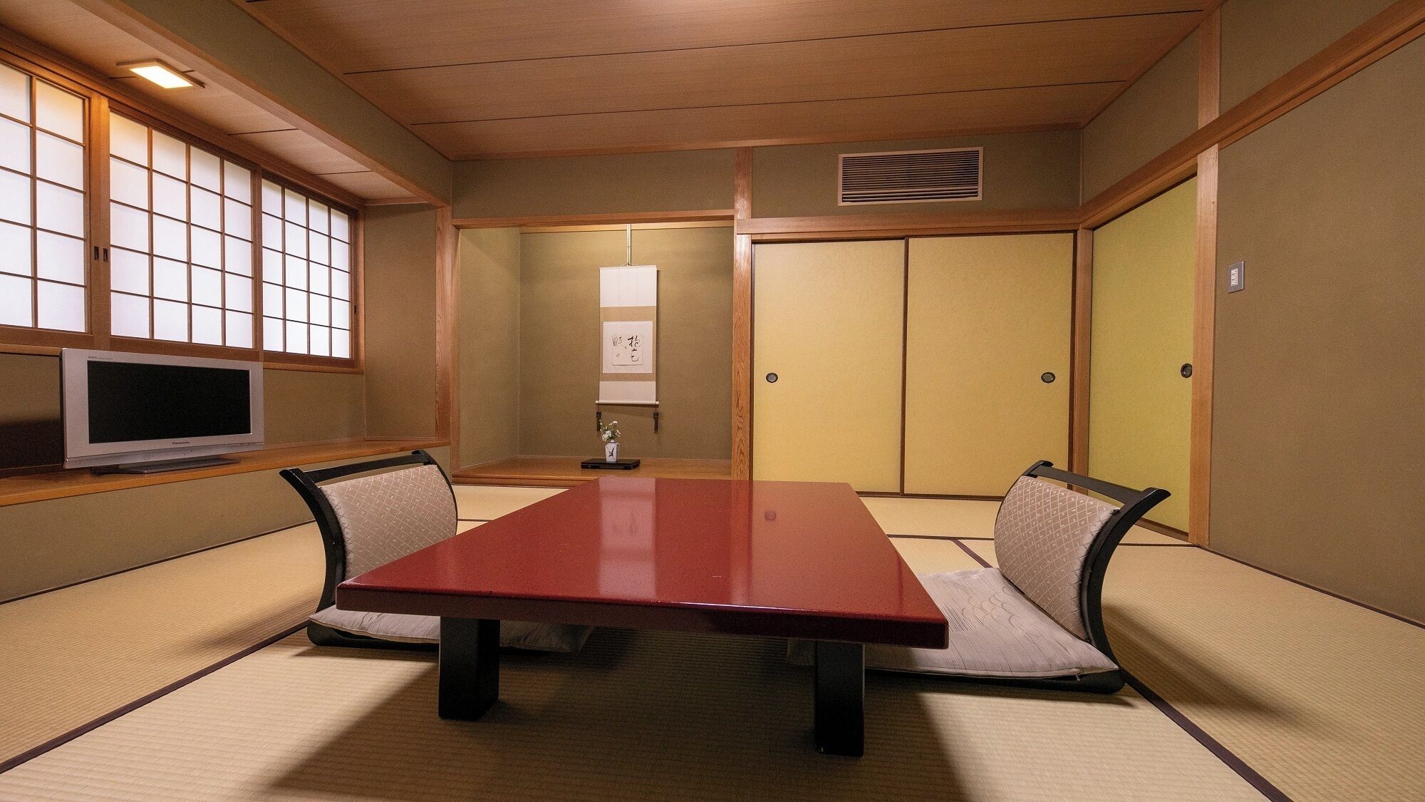 Una habitación japonesa tradicional con suelo de tatami, una mesa baja y puertas correderas shoji.