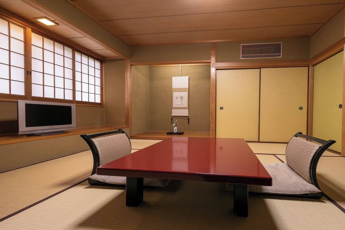 Una habitación japonesa tradicional con suelo de tatami, una mesa baja y puertas correderas shoji.