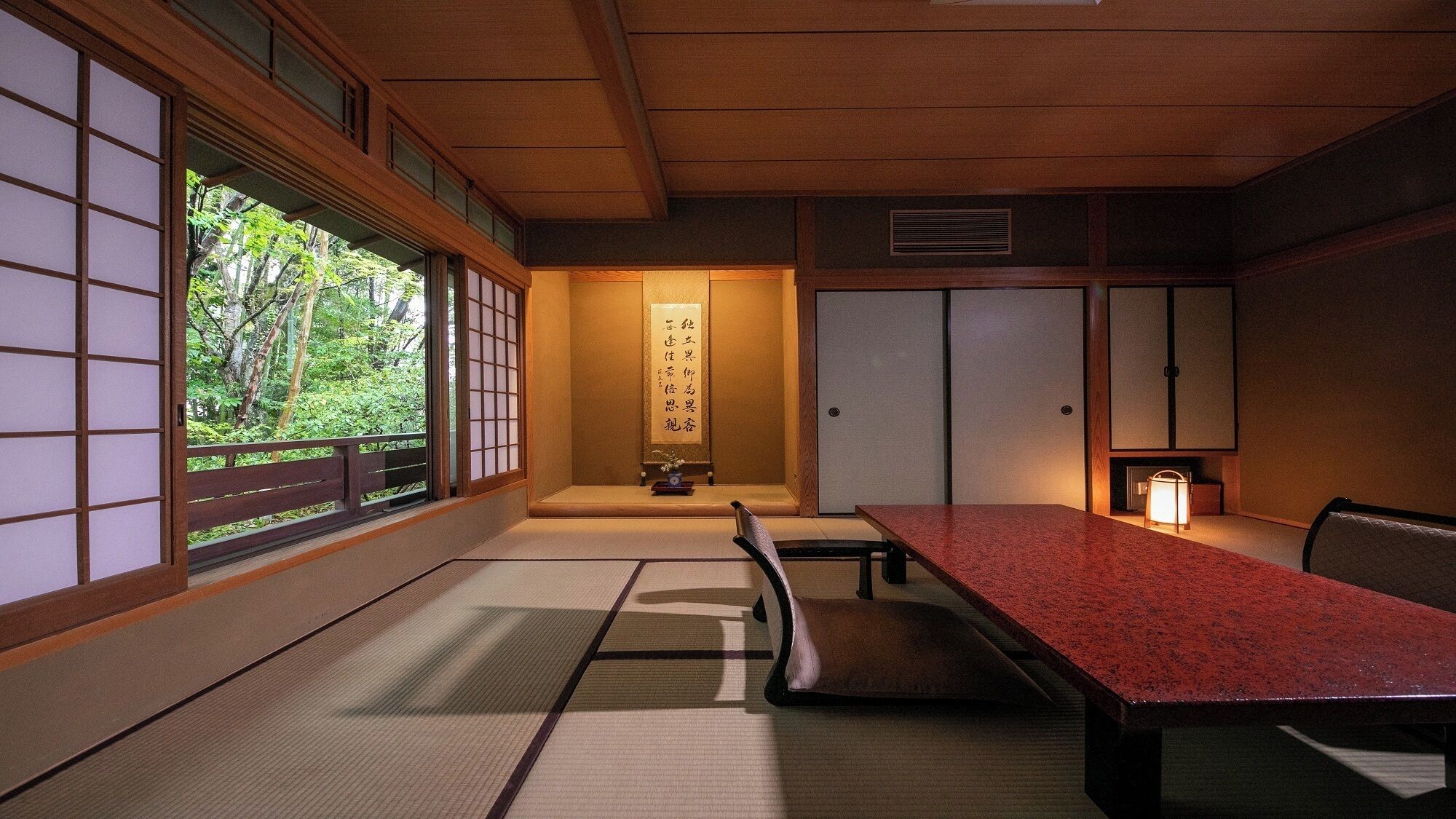 Una habitación japonesa tradicional con suelo de tatami, una mesa baja y puertas correderas.