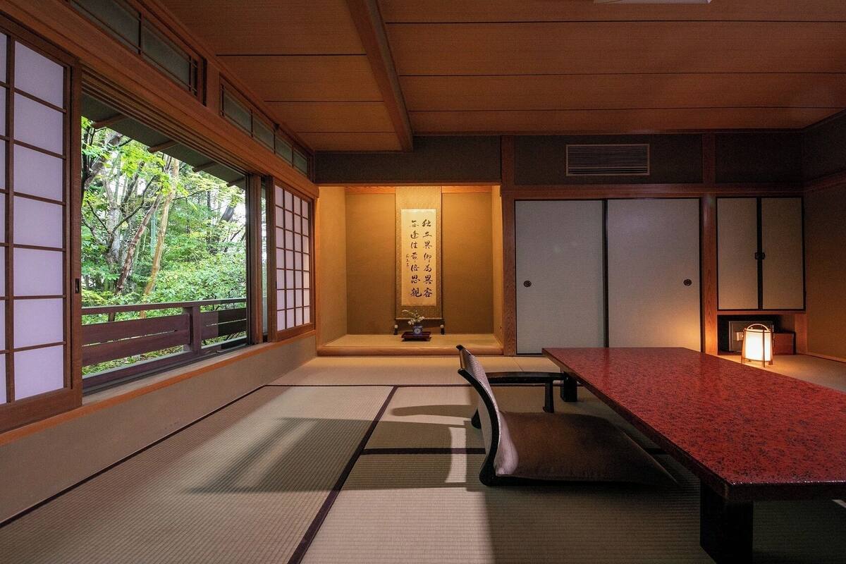 Una habitación japonesa tradicional con suelo de tatami, una mesa baja y puertas correderas.