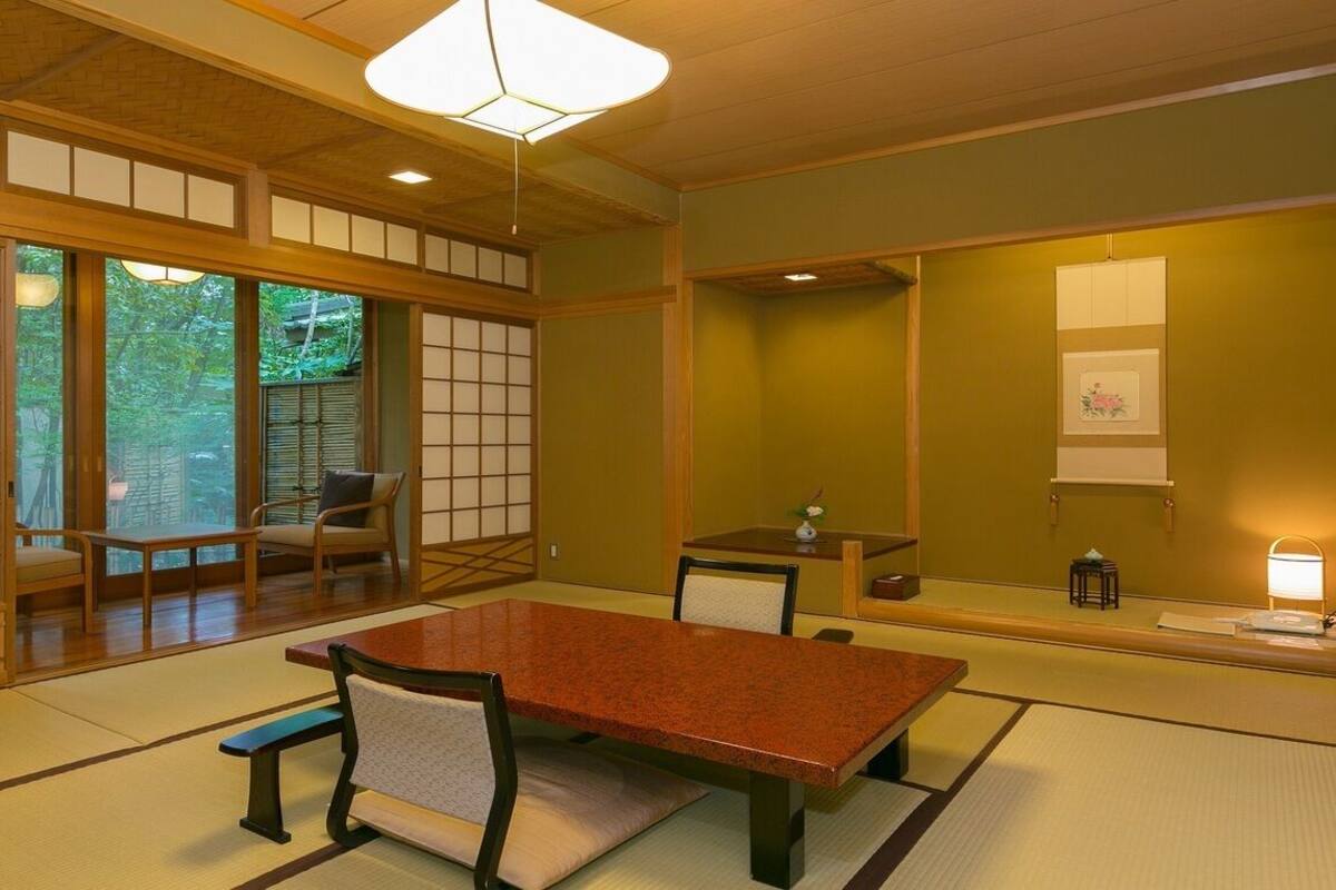 Una habitación japonesa tradicional con suelo de tatami, una mesa baja y puertas correderas.
