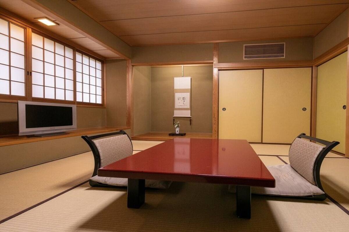 Una habitación tradicional japonesa con suelo de tatami, una mesa baja y puertas correderas.