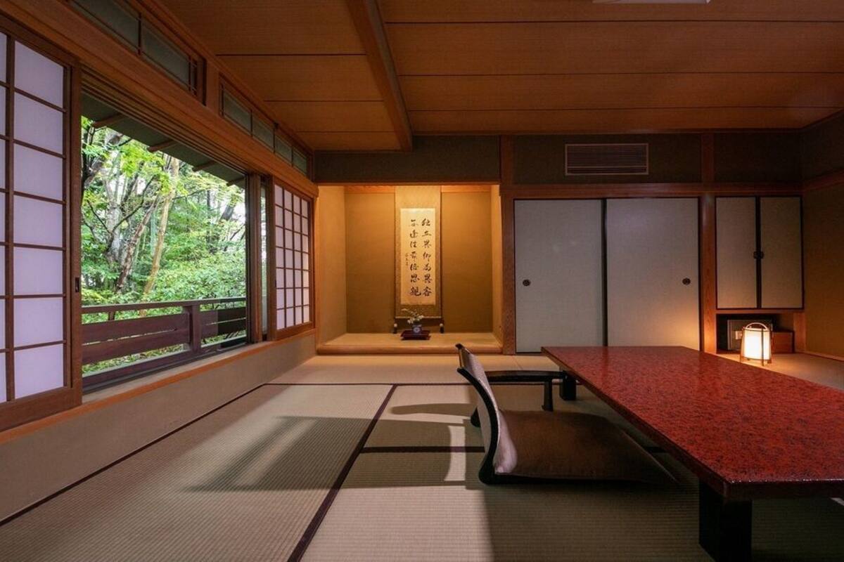 Una habitación japonesa tradicional con suelo de tatami, una mesa baja y puertas correderas.