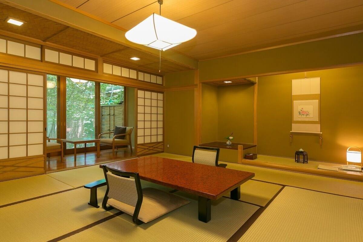 Una habitación japonesa tradicional con suelo de tatami, una mesa baja y puertas correderas.