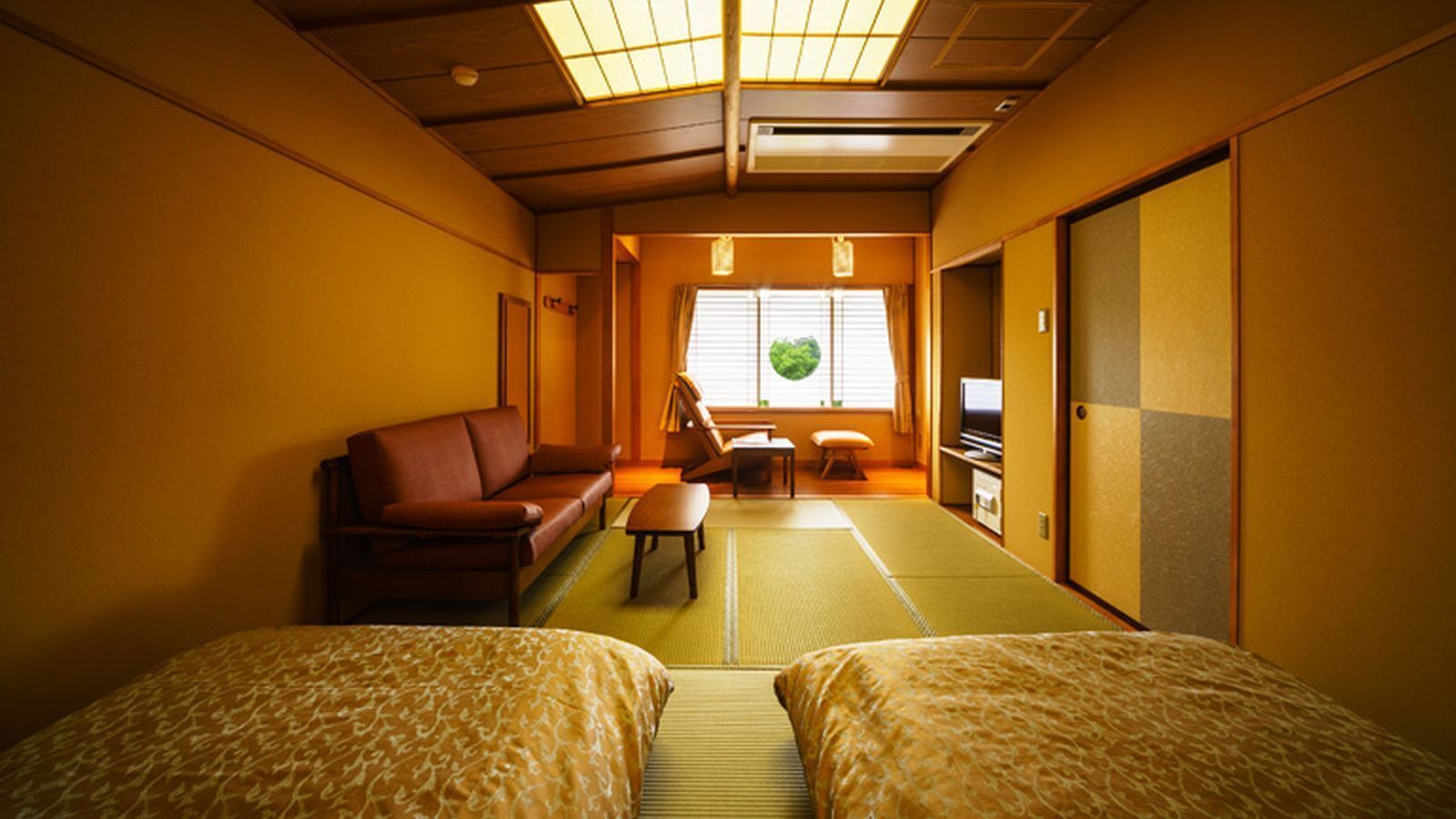 A traditional Japanese room with tatami flooring, a futon bed, a low wooden table, and a sliding door.