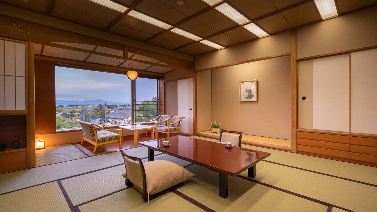 A traditional Japanese room with tatami flooring, a low table, and chairs.