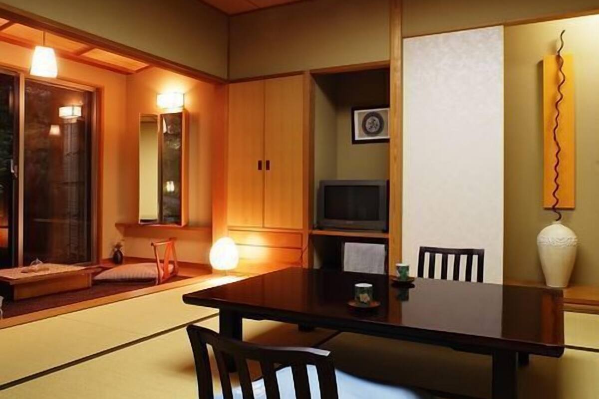 Ein traditioneller japanischer Raum mit Tatami-Böden, einem niedrigen Tisch und Stühlen.
