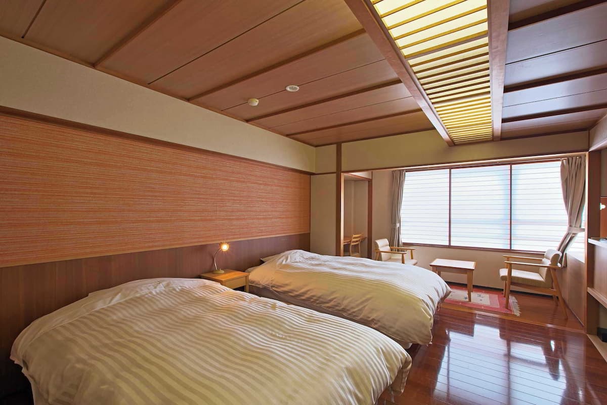 Une chambre d’hôtel avec deux lits, un bureau et une chaise.