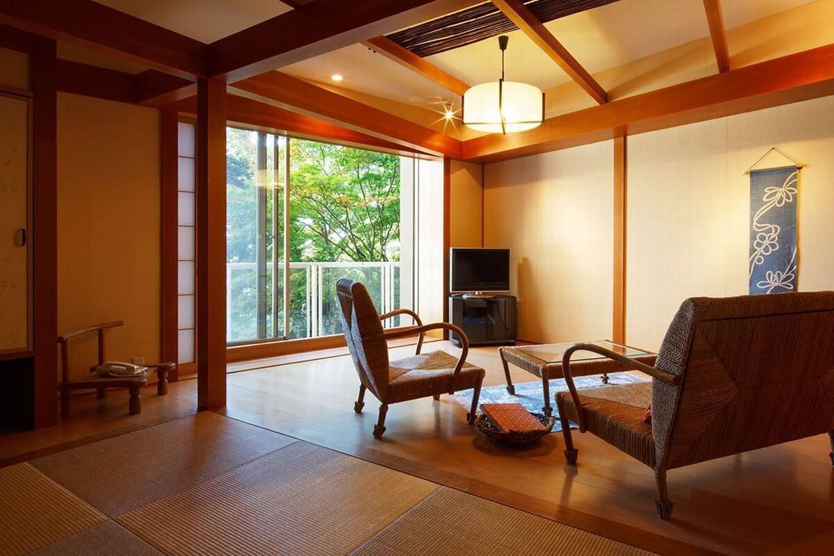 Ein traditioneller japanischer Raum mit Tatami-Boden, einem niedrigen Tisch und zwei Stühlen.