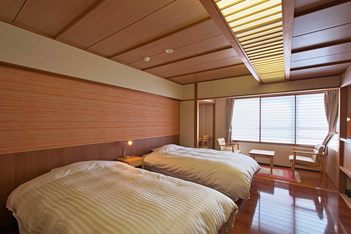Ein Zimmer mit zwei Betten, einem Schreibtisch und einem Stuhl.