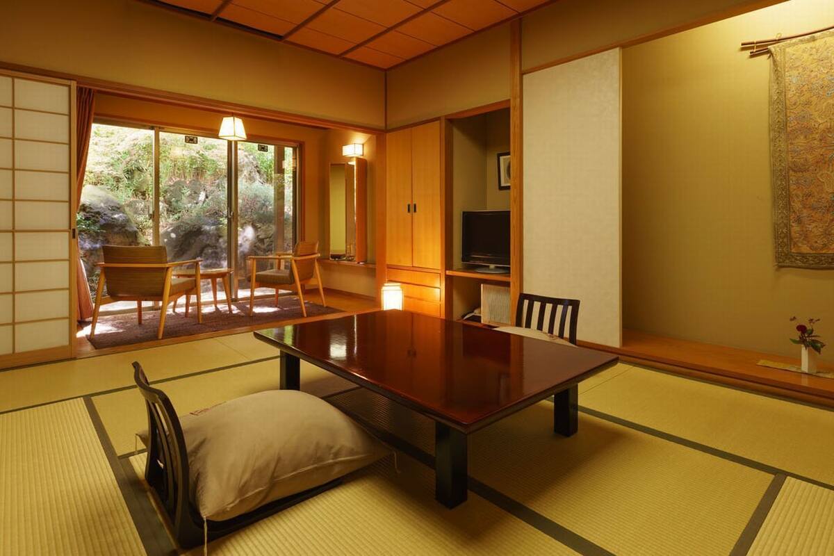 Ein traditioneller japanischer Raum mit Tatami-Boden, einem niedrigen Tisch und Schiebetüren.